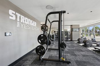 A gym with a wall that says "STRONGER THAN YESTERDAY" and a weightlifting machine at Dominion Post Oak apartments in Houston, TX
